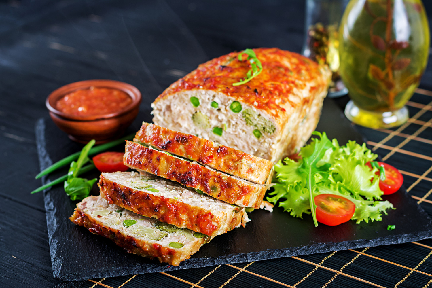 A simple and savory meatloaf, topped with a glossy glaze, served with mashed potatoes and vegetables on a dinner plate.