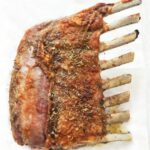 Golden roasted lamb rack with crispy crust and fresh herbs, served as an elegant main dish.